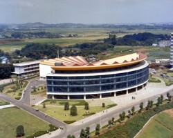 現在と比較すると周囲も広々として芝生も多いことがわかります。左後方に体育望星学塾(現 湘南クラブハウス)、さらに後ろに第二職員住宅を確認することができます。特に大学構内と外部を隔てる鉄柵の塀がないことにご注目ください。 空から見た2号館と周辺